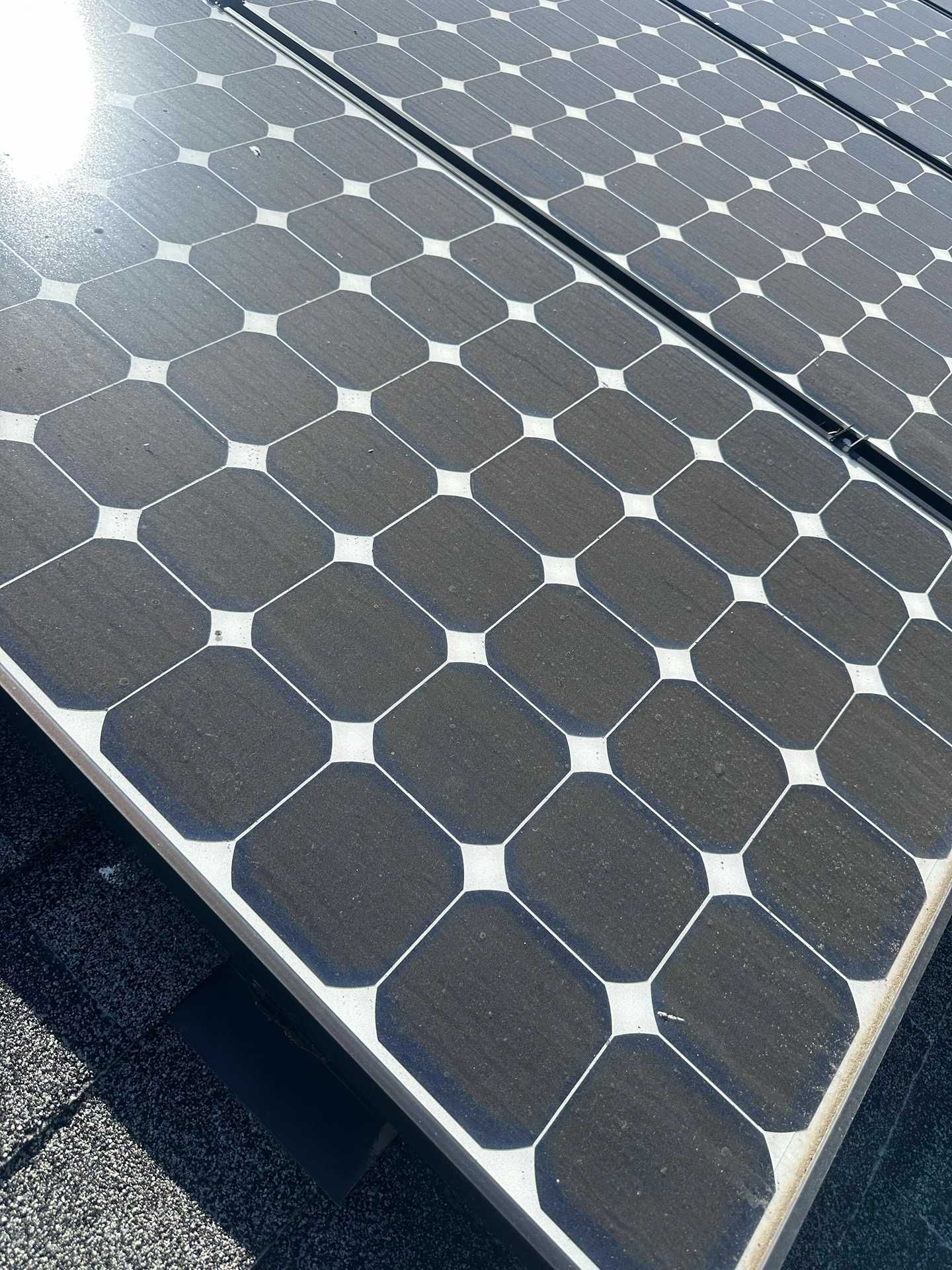 Solar panels with hexagonal cells on a rooftop in bright sunlight.