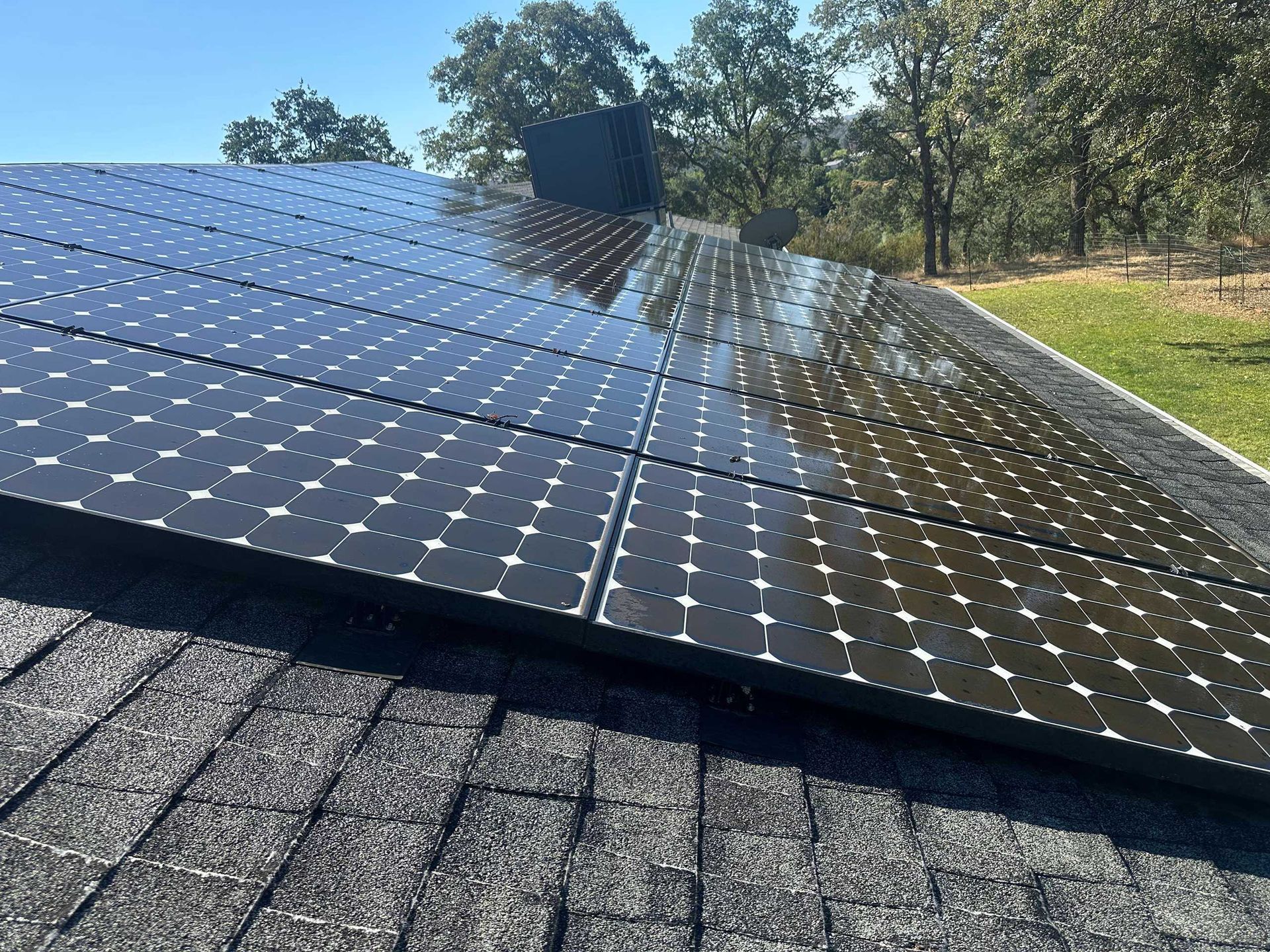 Solar panels installed on a sloped roof, reflecting sunlight under a clear sky.