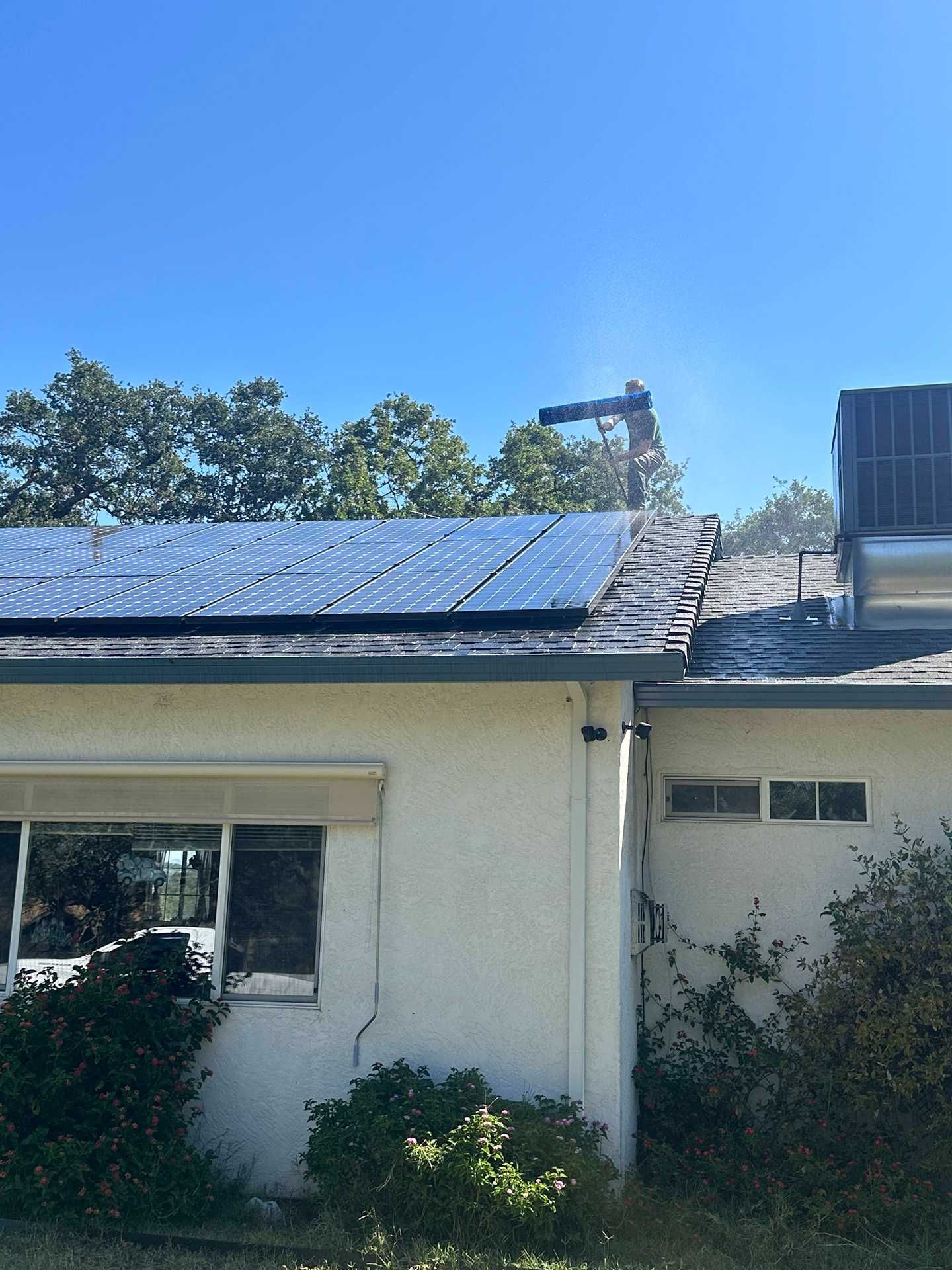 Single-story house with rooftop solar panels under a clear blue sky.