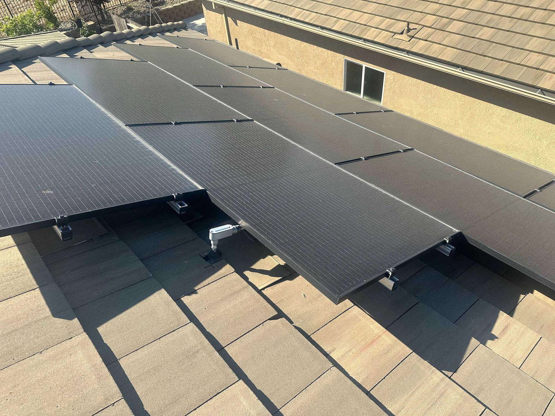 Black solar panels mounted on a tiled rooftop in sunlight