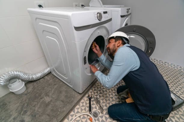 A man is fixing a washing machine in a laundry room.