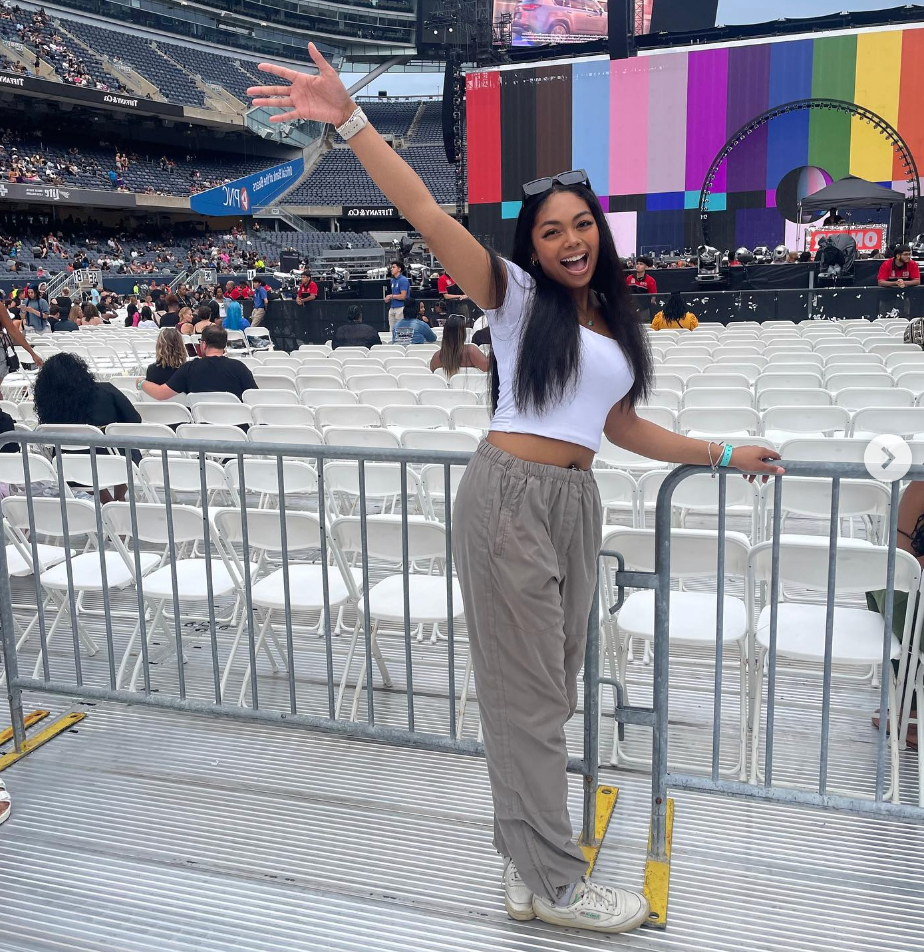 A woman is standing next to a fence with her arm in the air