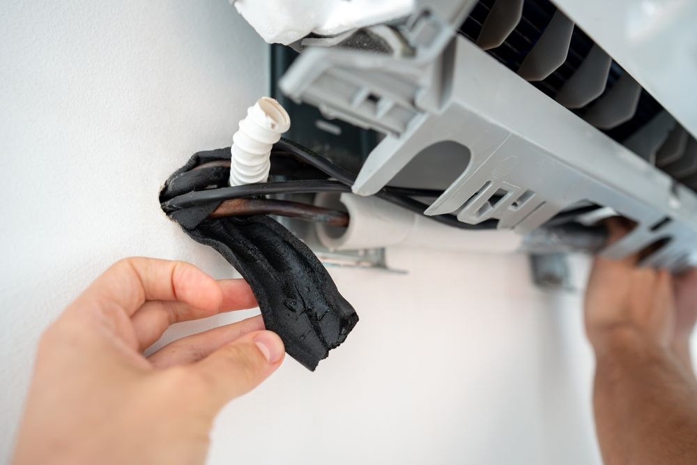 Technician cleaning a wall-mounted air conditioner with a cloth
