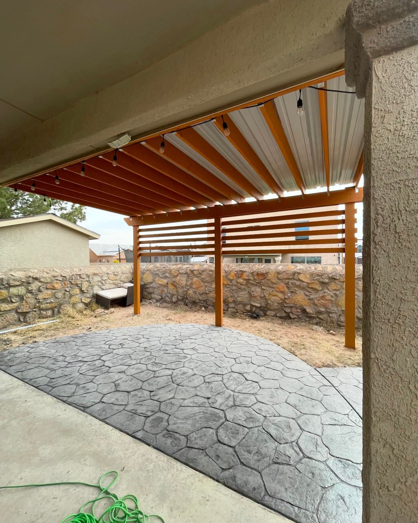 Covered patio with stone floor, wooden posts, and a retractable awning over a shaded outdoor area
