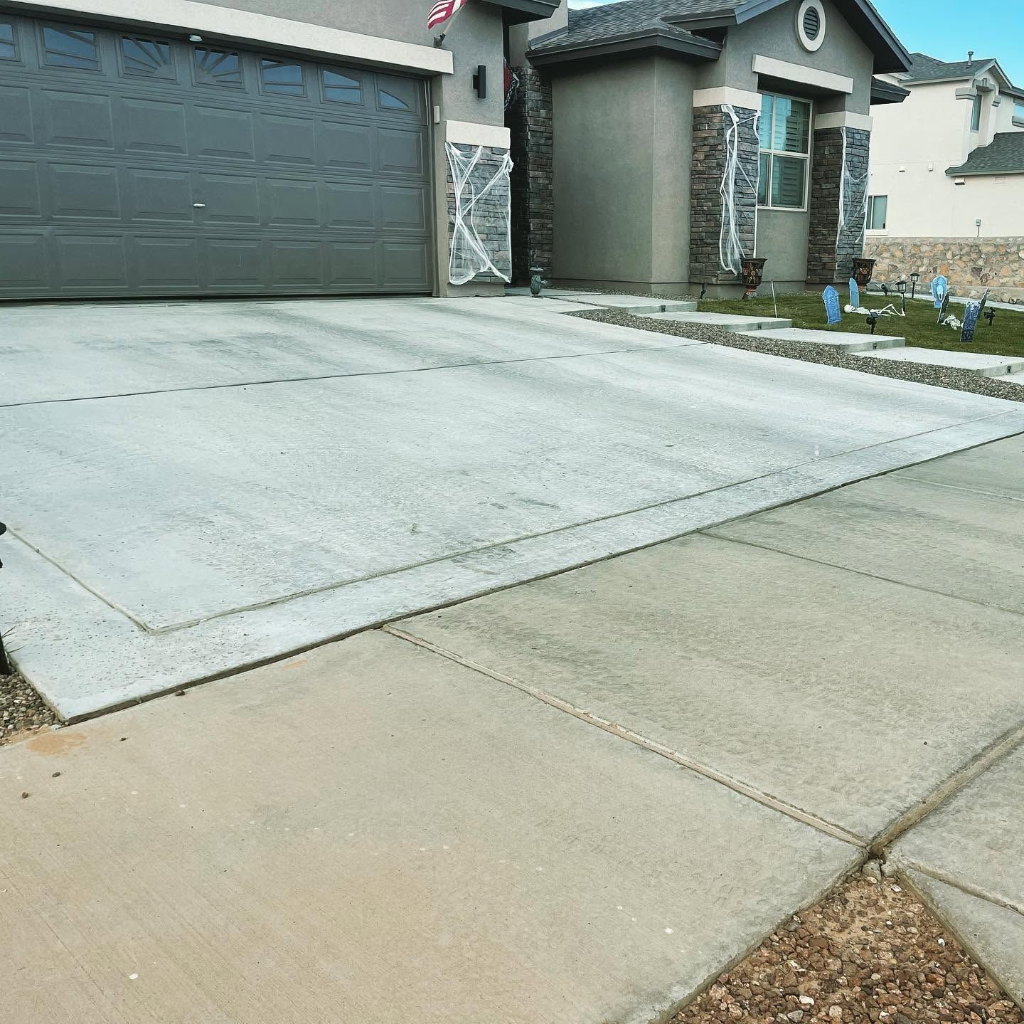 Suburban house with a two-car garage and a wide concrete driveway leading to the street.