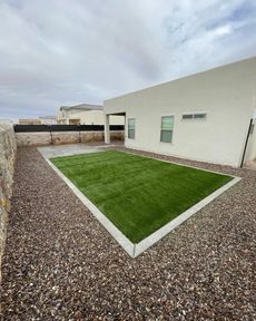 Modern house patio with gravel border and a small rectangular green lawn under a cloudy sky