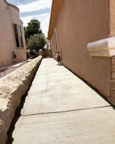 Narrow concrete walkway between beige stucco buildings in bright sunlight