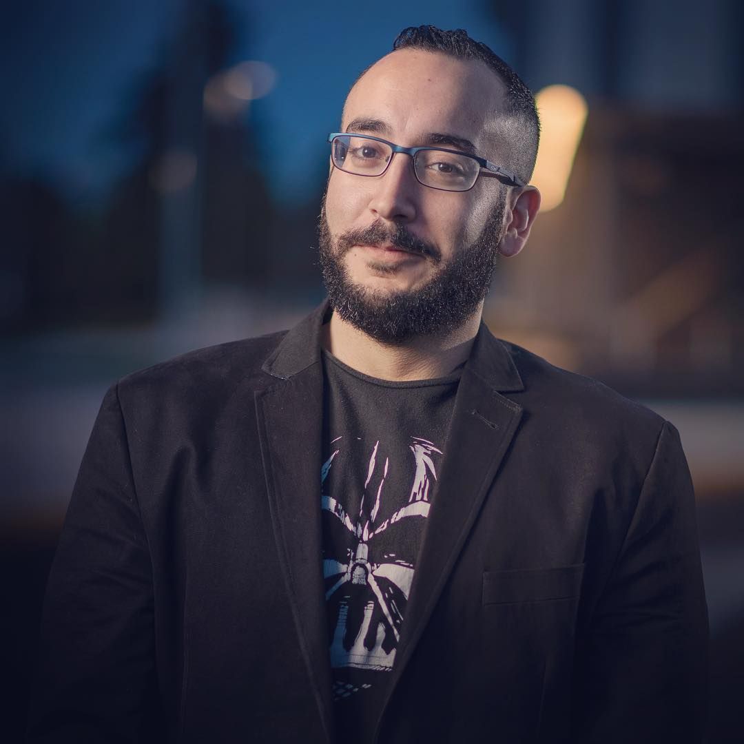 A man with a beard wearing glasses and a black jacket
