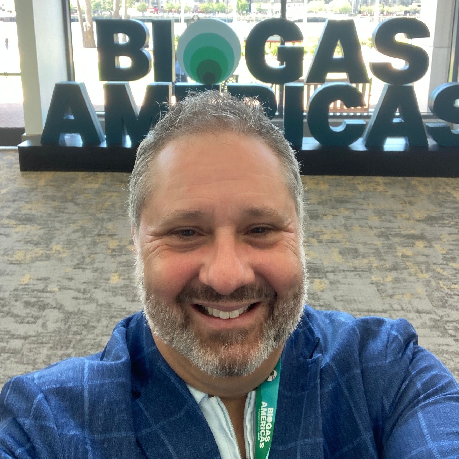A man is smiling in front of a sign that says biogas americas