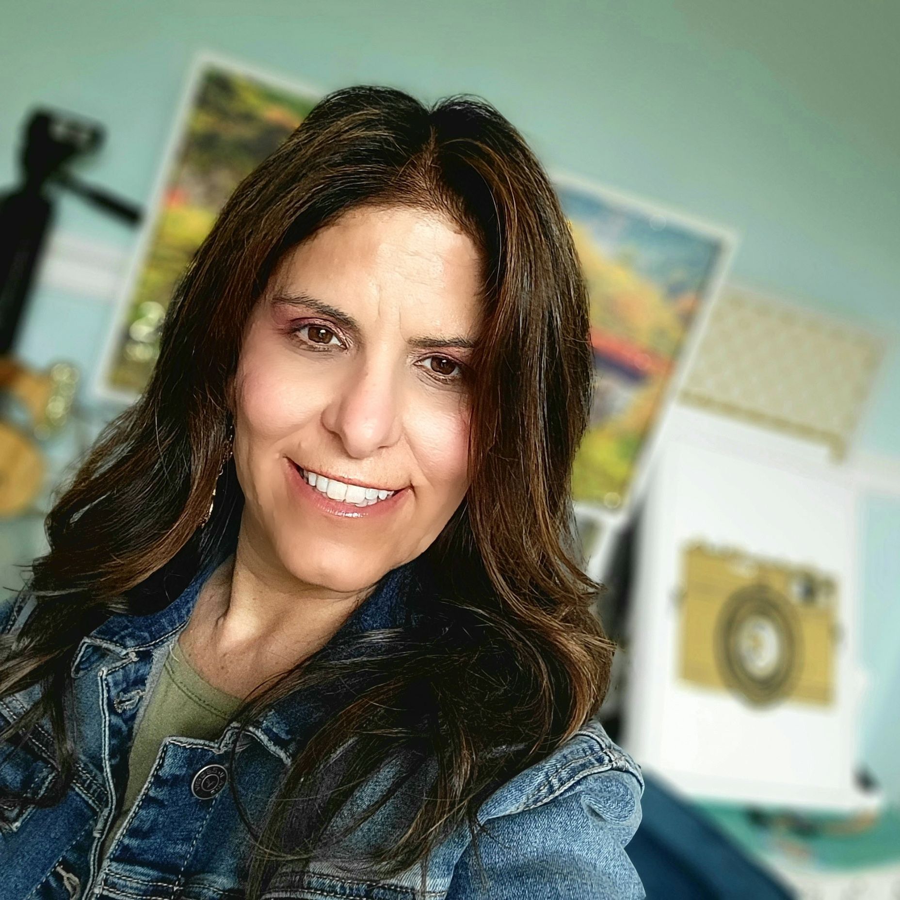 A woman in a denim jacket is smiling for the camera