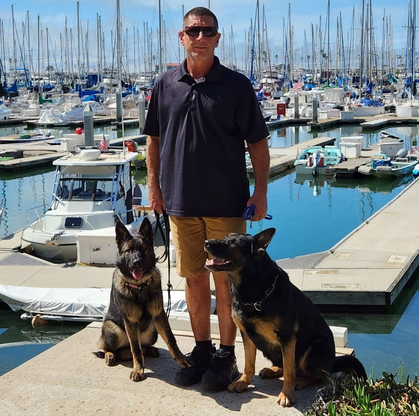 Rich Rosen, owner of Dockside Dog Training, with two German Shepherds at a marina. 