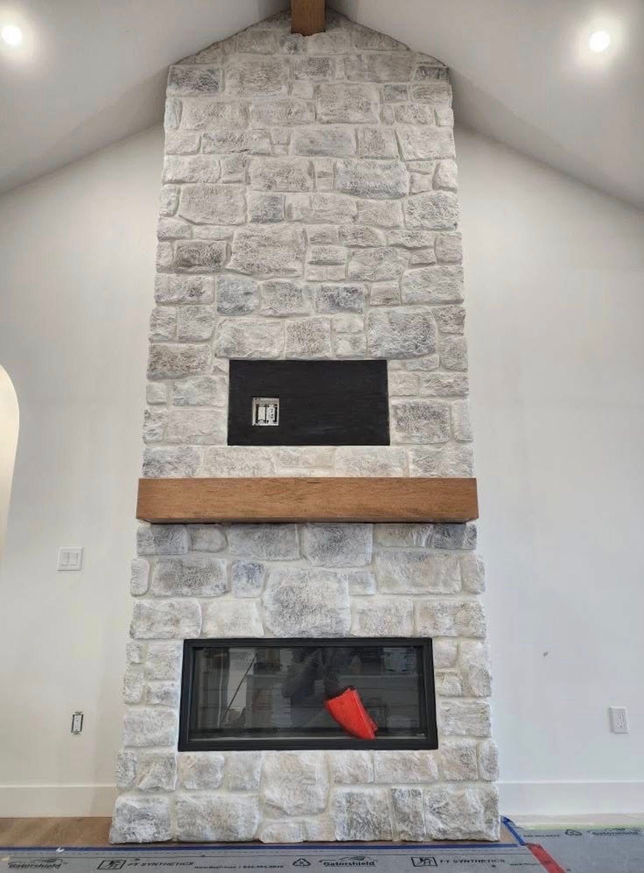 Stone fireplace with black inset and wooden beam.