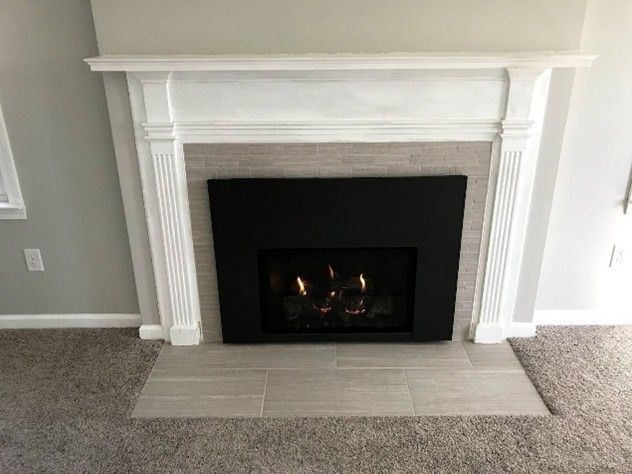 White fireplace mantel with black fireplace insert and tile hearth.