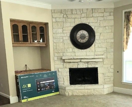 Fireplace with stone surround, built-in cabinets, and a flat-screen TV box.