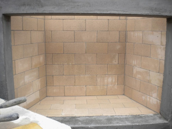 Brick-lined fireplace interior with tan bricks and gray concrete surround.