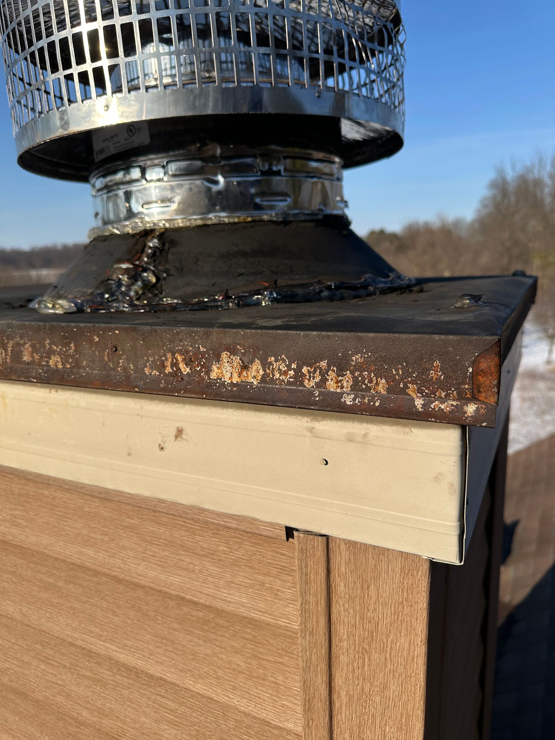 Rusty roof vent on a shingled roof under a blue sky