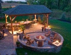 Outdoor patio with stone fireplace, seating area, and cable railing.