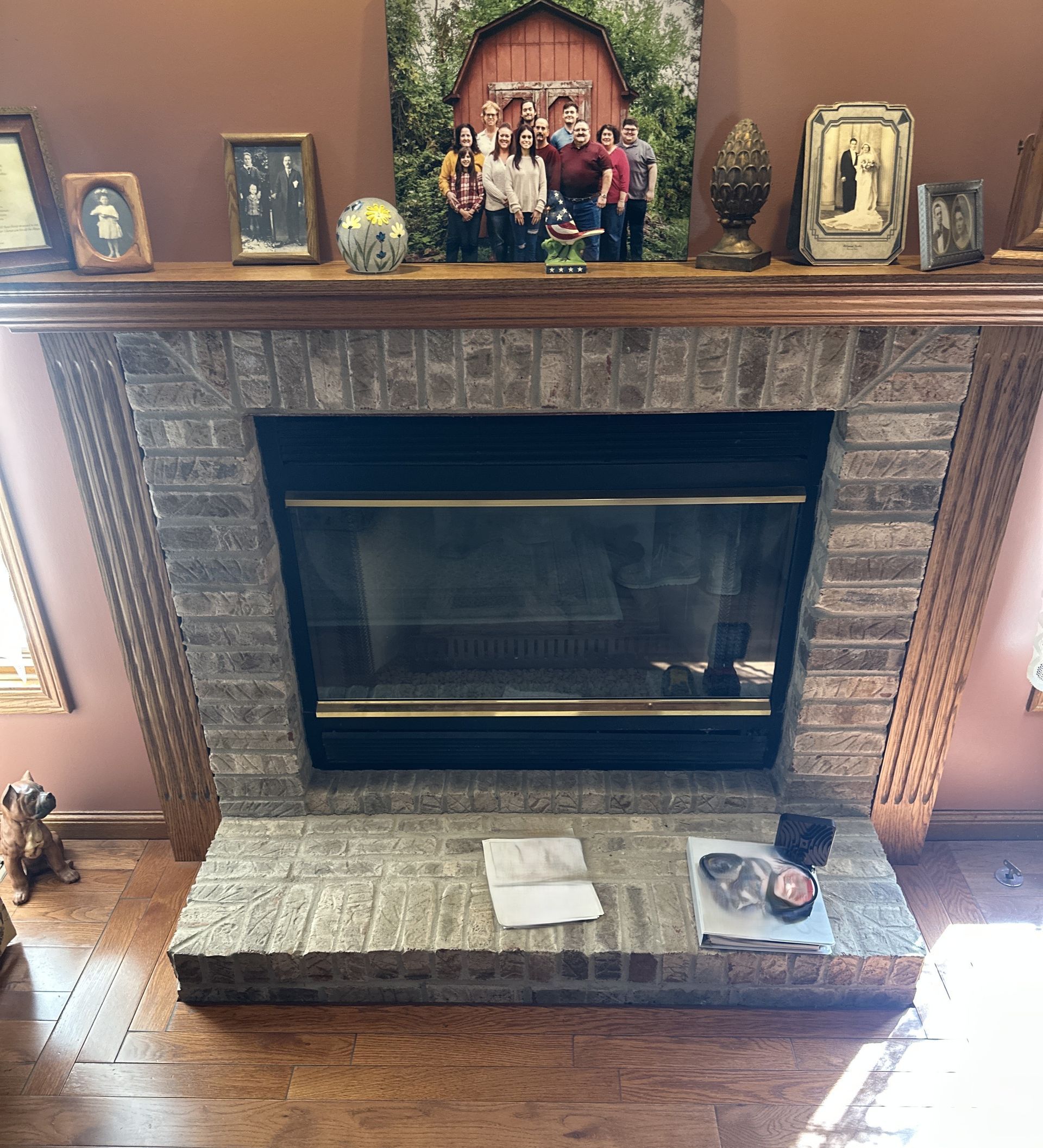 Stone fireplace with mantel, framed photos, and family portraits in a living room