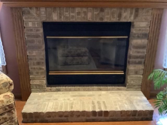 Brick fireplace with black insert and beige hearth in a living room