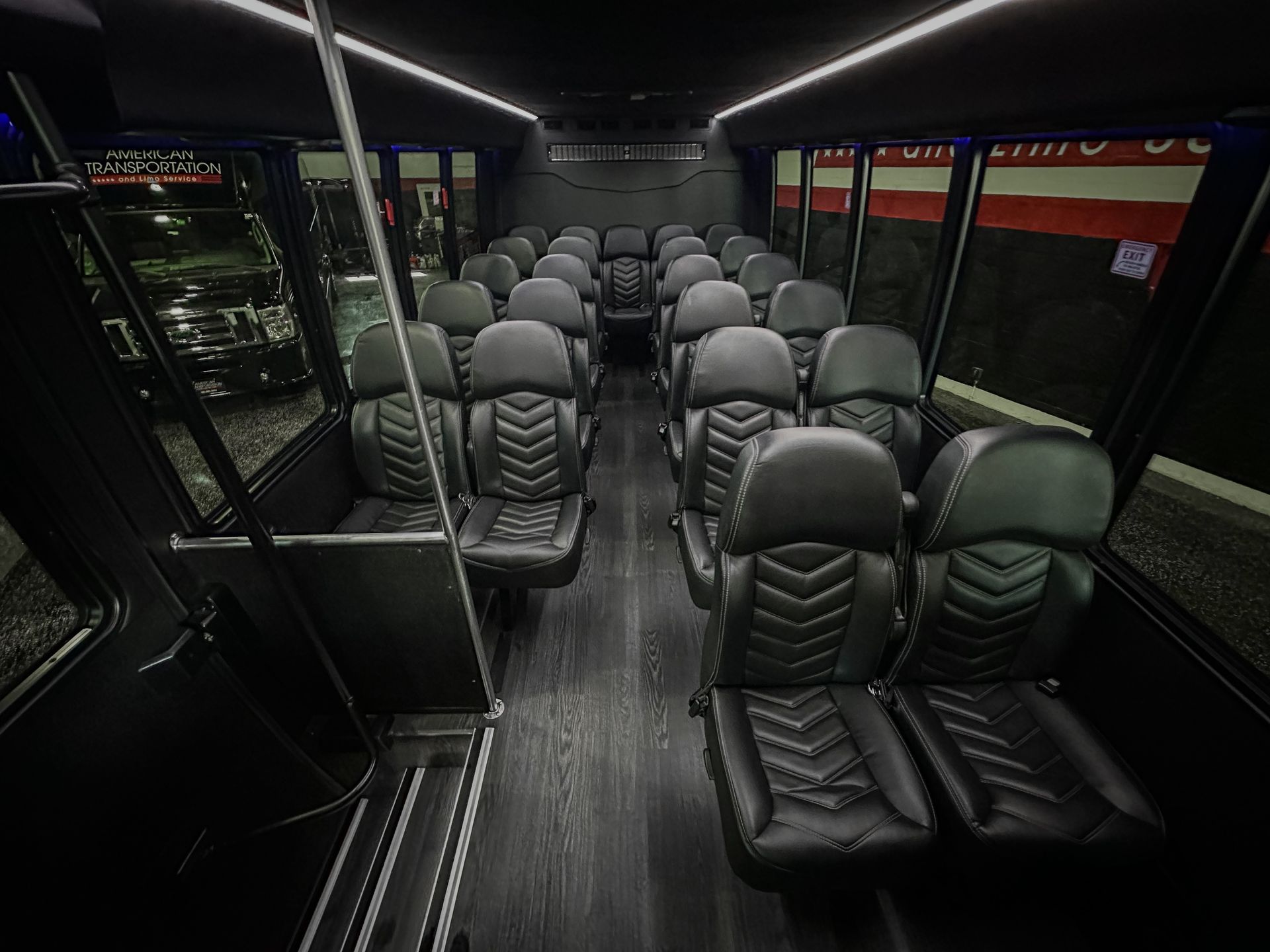Shuttle bus interior with rows of black leather passenger seats.