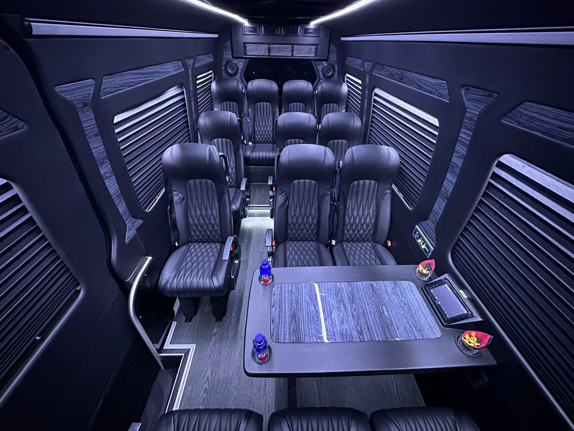 Executive Sprinter van interior with quilted leather captain's chairs, a workstation table, and premium amenities.