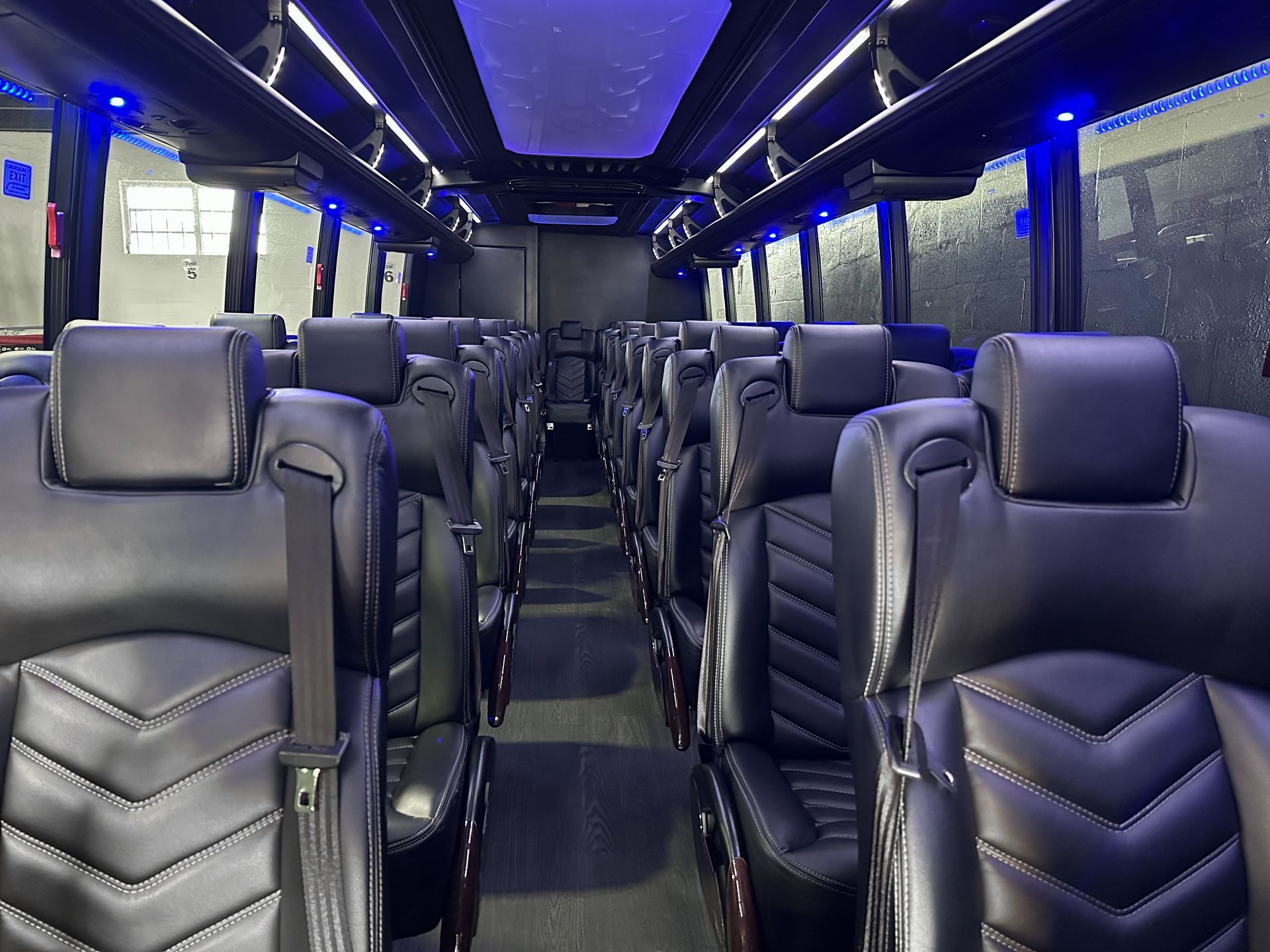 Luxury shuttle bus interior with reclining leather seats and ambient LED lighting.