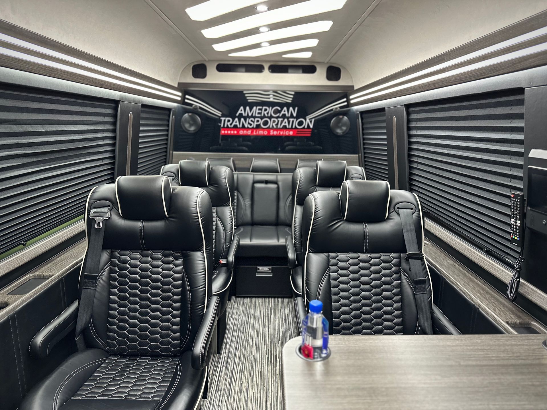 Luxury executive van interior with reclining leather captain's chairs, premium lighting, and spacious seating.