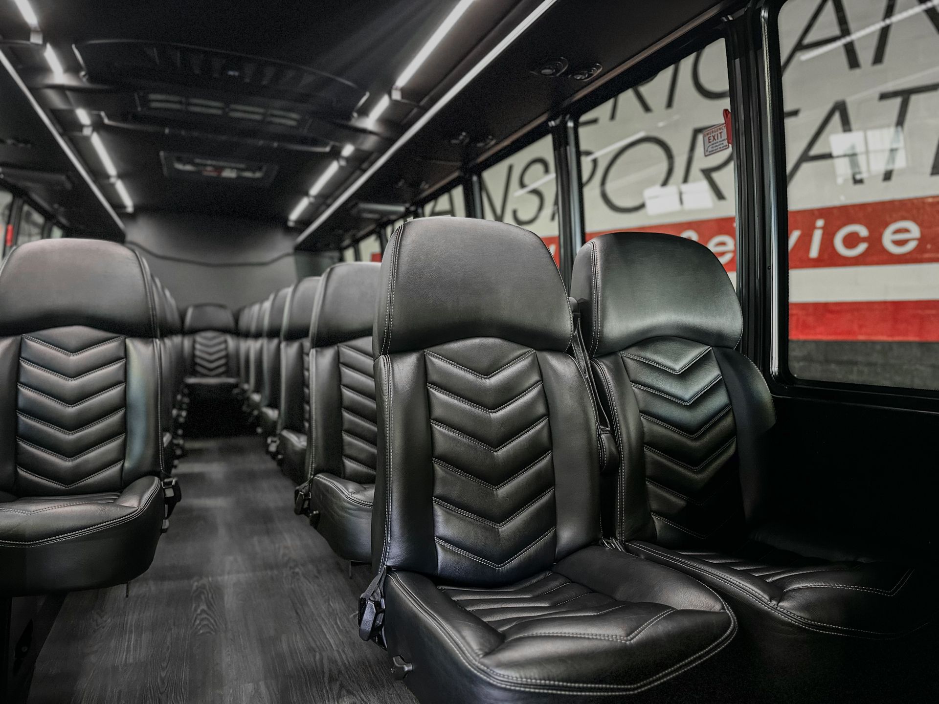 Interior of an executive mini coach with rows of premium leather seats, spacious aisle, and modern lighting.