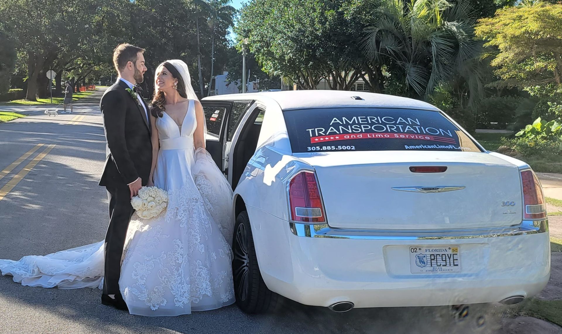 Bride and groom standing beside a white wedding limousine before departure in Miami, FL