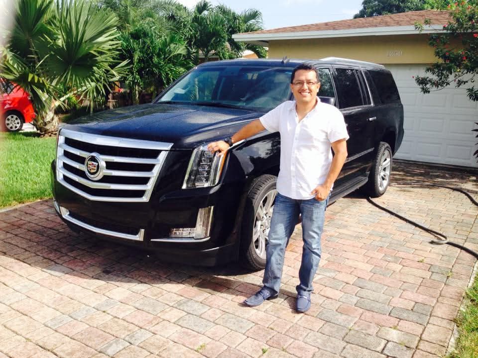 Man standing beside a black Cadillac Escalade used for private car service in Miami.