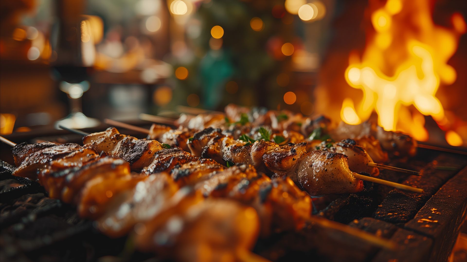Grilled meat skewers on a grill with a fire burning in the background.