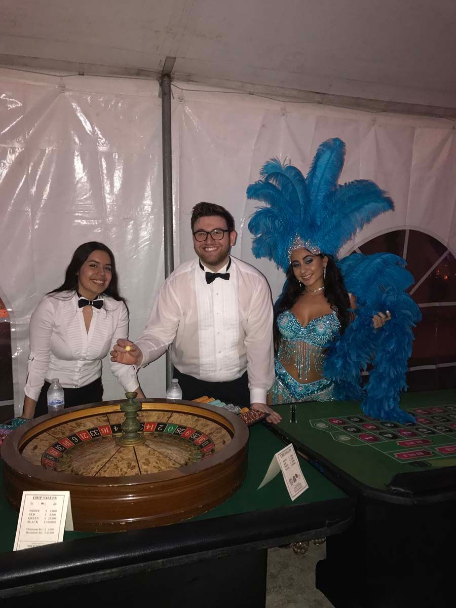 Croupiers and showgirls at roulette wheel.