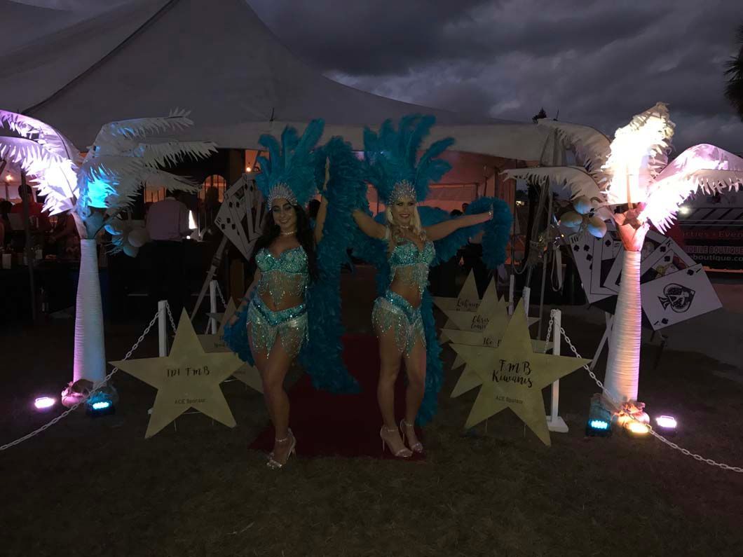 Showgirls greeting guests with red carpet and lighted canvas palm trees.