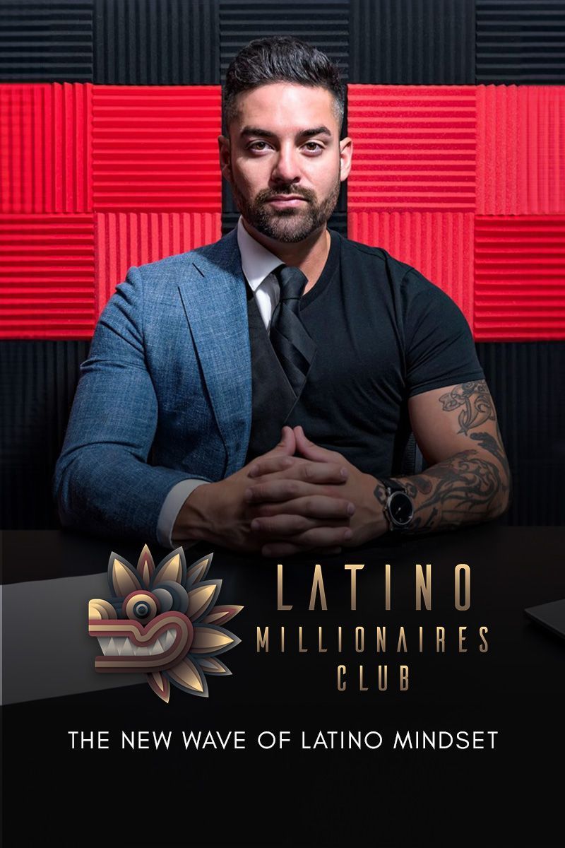 Rico in a suit and tie is sitting in front of a red and black wall .