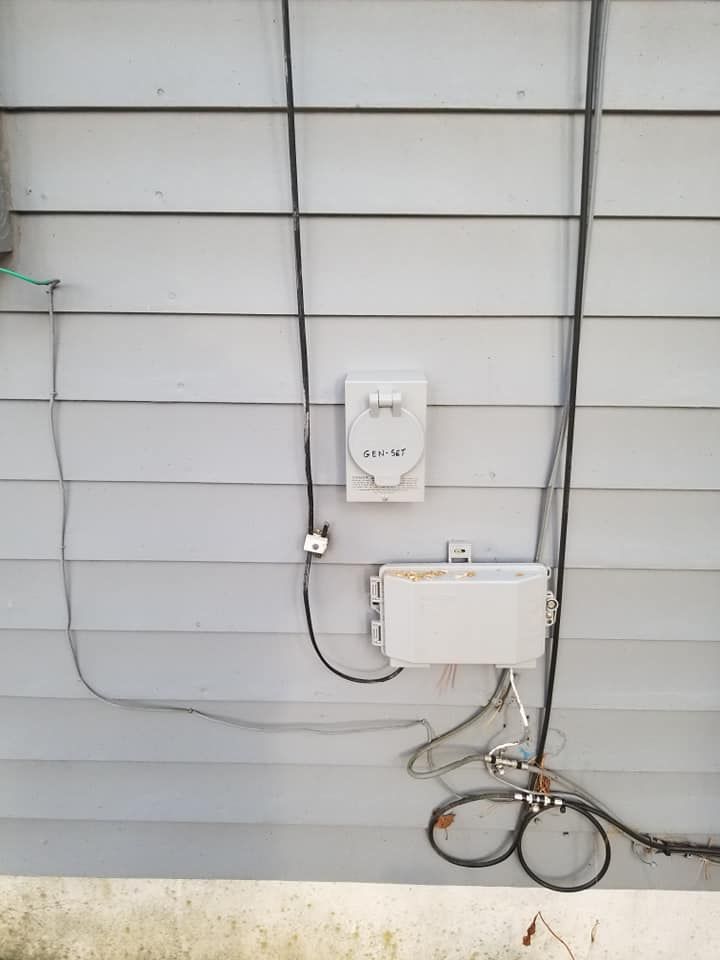 Exterior house wall with electrical meter, utility boxes, and exposed cables.