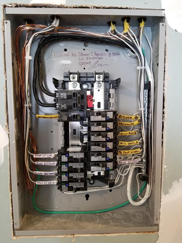 Open electrical breaker panel with exposed wires and multiple switches in a wall-mounted metal box