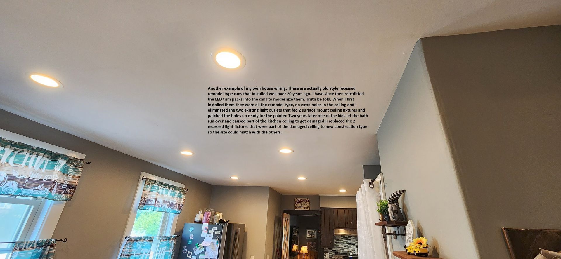 Living room with recessed ceiling lights, windows, and a wall quote above a dining area