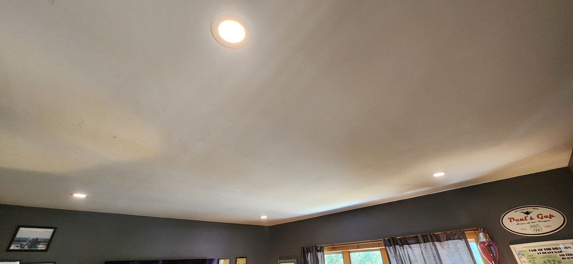 Upward view of a curved white ceiling with recessed lights in a living room