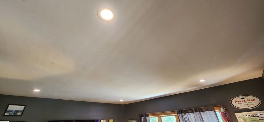 Living room ceiling with recessed lights and a central dome light above dark walls and windows