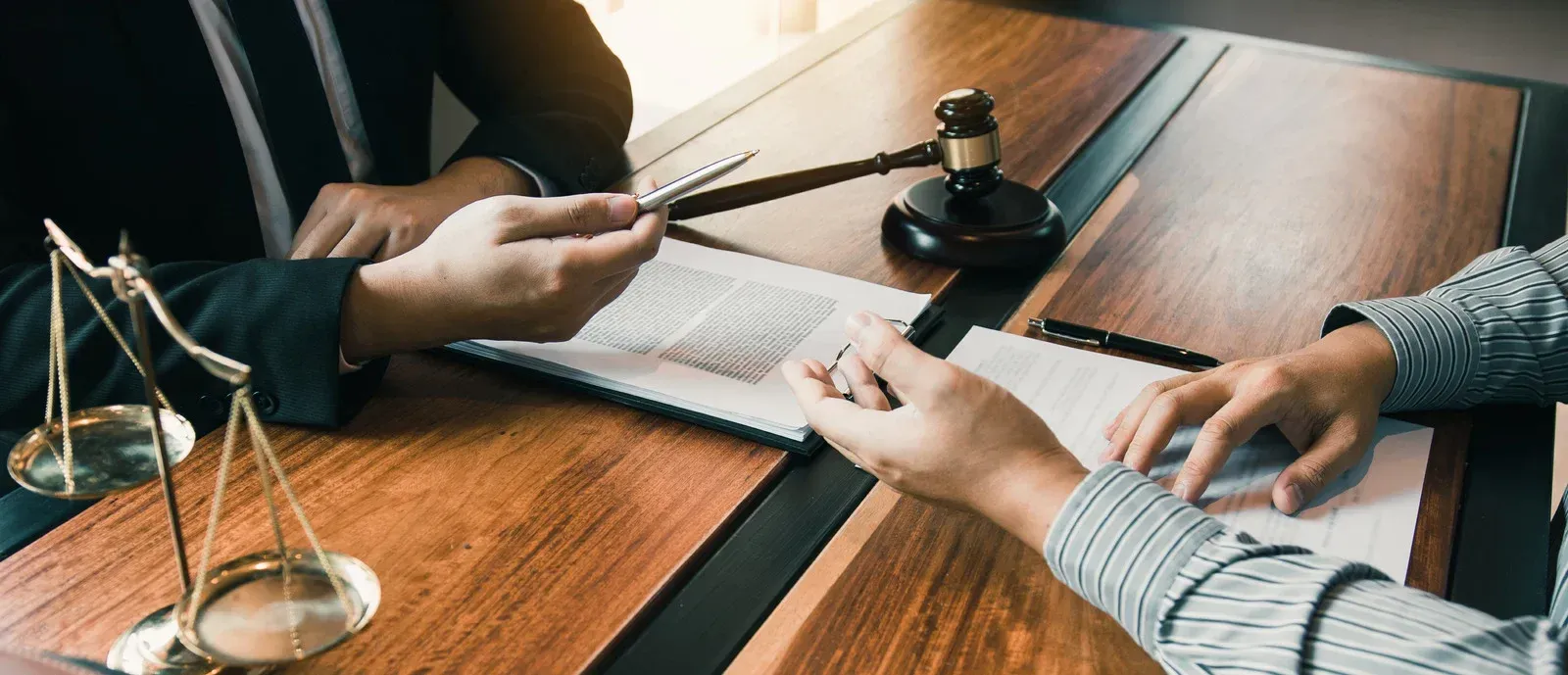 Two people are sitting at a table with scales of justice and a judge 's gavel.