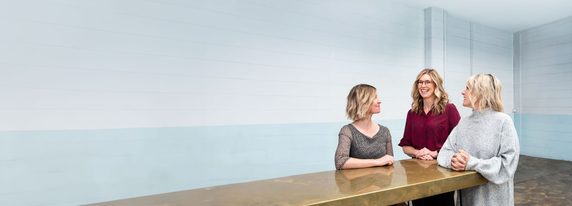 Three women are sitting at a table talking to each other.