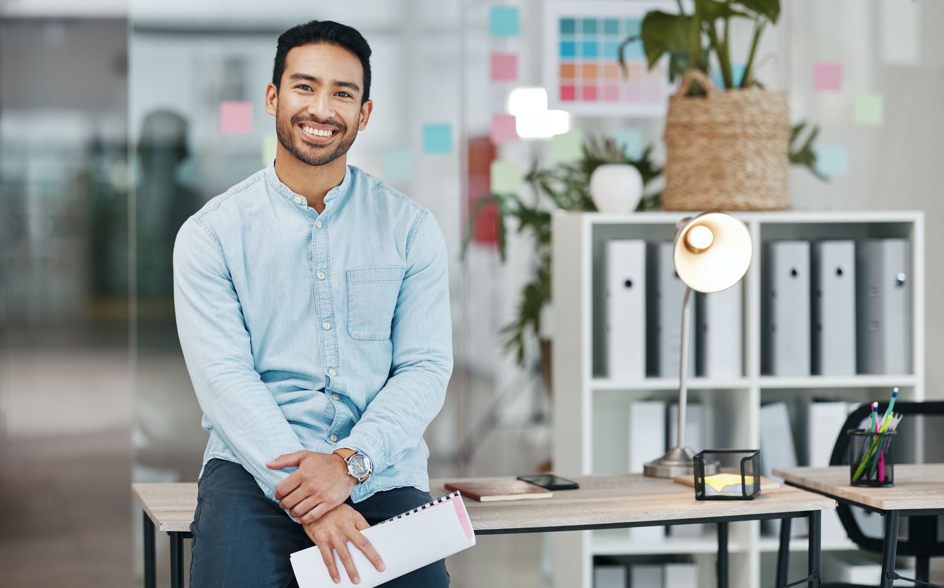 A man is sitting at a desk in an office holding a piece of paper.