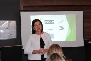 A woman is giving a presentation in front of a projector screen.
