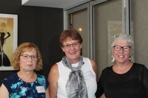 Three women are posing for a picture together in a room.