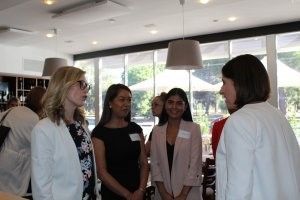 A group of women are standing in a room talking to each other.