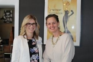 Two women are standing next to each other in front of a poster.