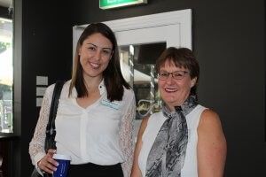 Two women are standing next to each other in a room and smiling.