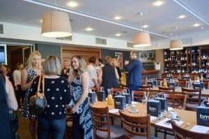 A group of people are standing in a restaurant talking to each other.