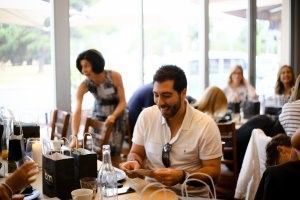 A man is sitting at a table in a restaurant looking at his phone.