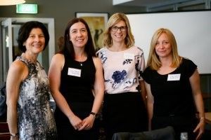 Four women are posing for a picture together in a room.
